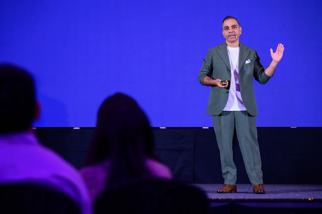 Prashant Saxena presenting in a green suit on stage